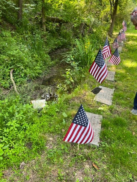 Close view of two flagged headstones near a small creek.